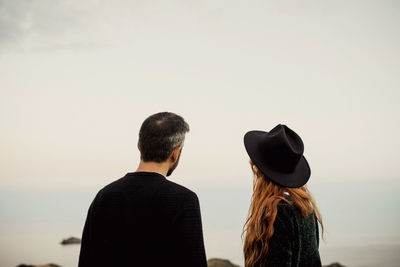 Rear view of friends standing against sky