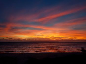 Scenic view of sea against dramatic sky during sunset