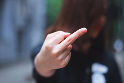 Close-up of woman showing obscene gesture