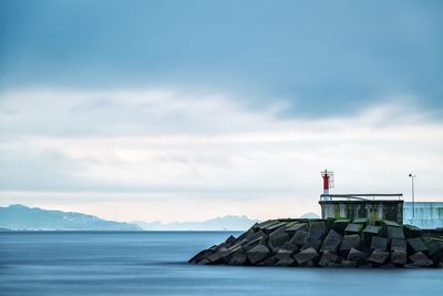 Lighthouse by sea against sky