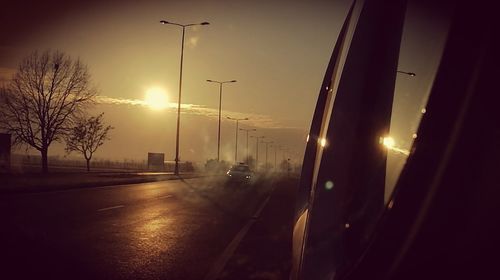 Illuminated road against sky during sunset