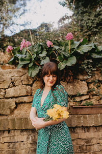 Portrait of smiling woman standing against wall