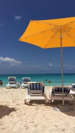Deck chairs on beach against blue sky