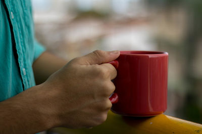 Cropped hand of man having coffee on railing