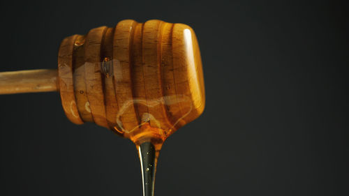 Close-up of honey dipper against black background