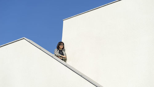 Low angle view of woman against blue sky