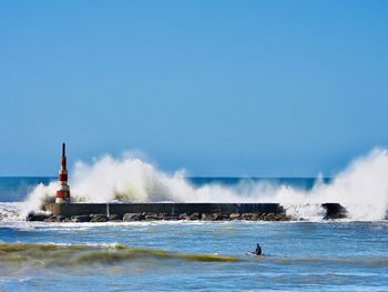 Waves crashing at light house amidst sea