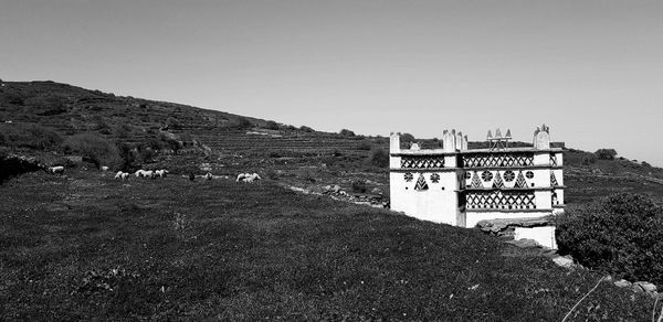 Information sign on field by building against clear sky