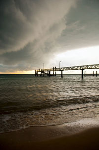 Pier over sea against sky during sunset