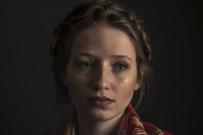 Portrait of beautiful young woman against black background