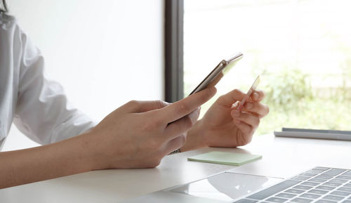 Midsection of man using smart phone on table