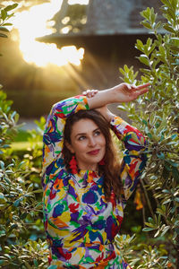 Portrait of young woman standing against plants