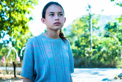 Portrait of young woman standing against trees