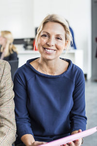 Portrait of mid adult businesswoman holding file while sitting at office restaurant