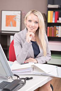 Portrait of businesswoman with file on desk while working in office