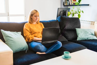 Portrait of young woman sitting on sofa at home