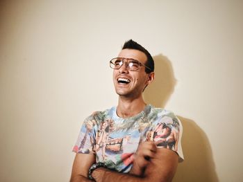 Young man wearing sunglasses while standing against wall