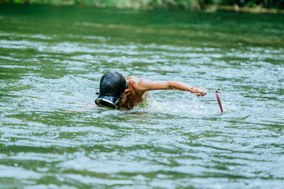 Rear view of shirtless man swimming in lake