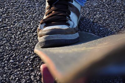 Cropped leg with skateboard on street