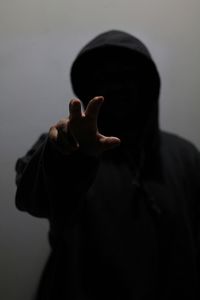 Close-up of man in hooded clothing gesturing against wall li