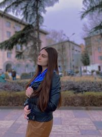 Beautiful young woman standing against tree