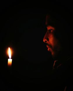 Close-up of illuminated candle against black background