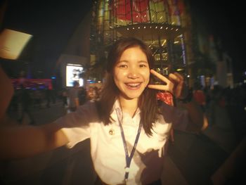 Portrait of smiling young woman using mobile phone at night