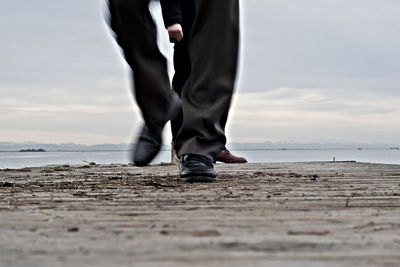 Low section of man walking on pier