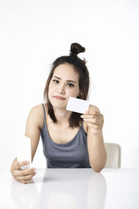 Portrait of smiling young woman using phone against white background