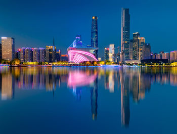 Reflection of buildings in city against blue sky