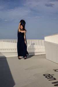 Woman standing on railing against sky