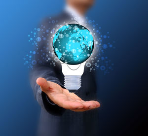 Digital composite image of businessman holding light bulb icon against blue background