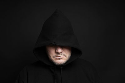 Man wearing hooded shirt against black background