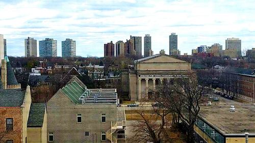 View of cityscape against cloudy sky