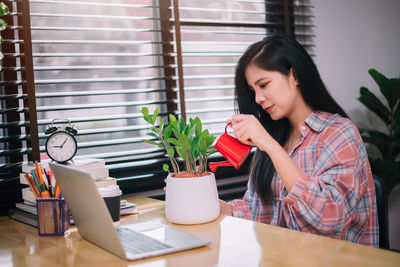 Young woman using mobile phone on table at home