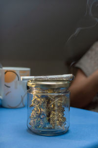 Close-up of hand holding glass jar on table