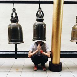 Man crouching against bell