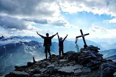 Rear view of friends standing on rocks against sky