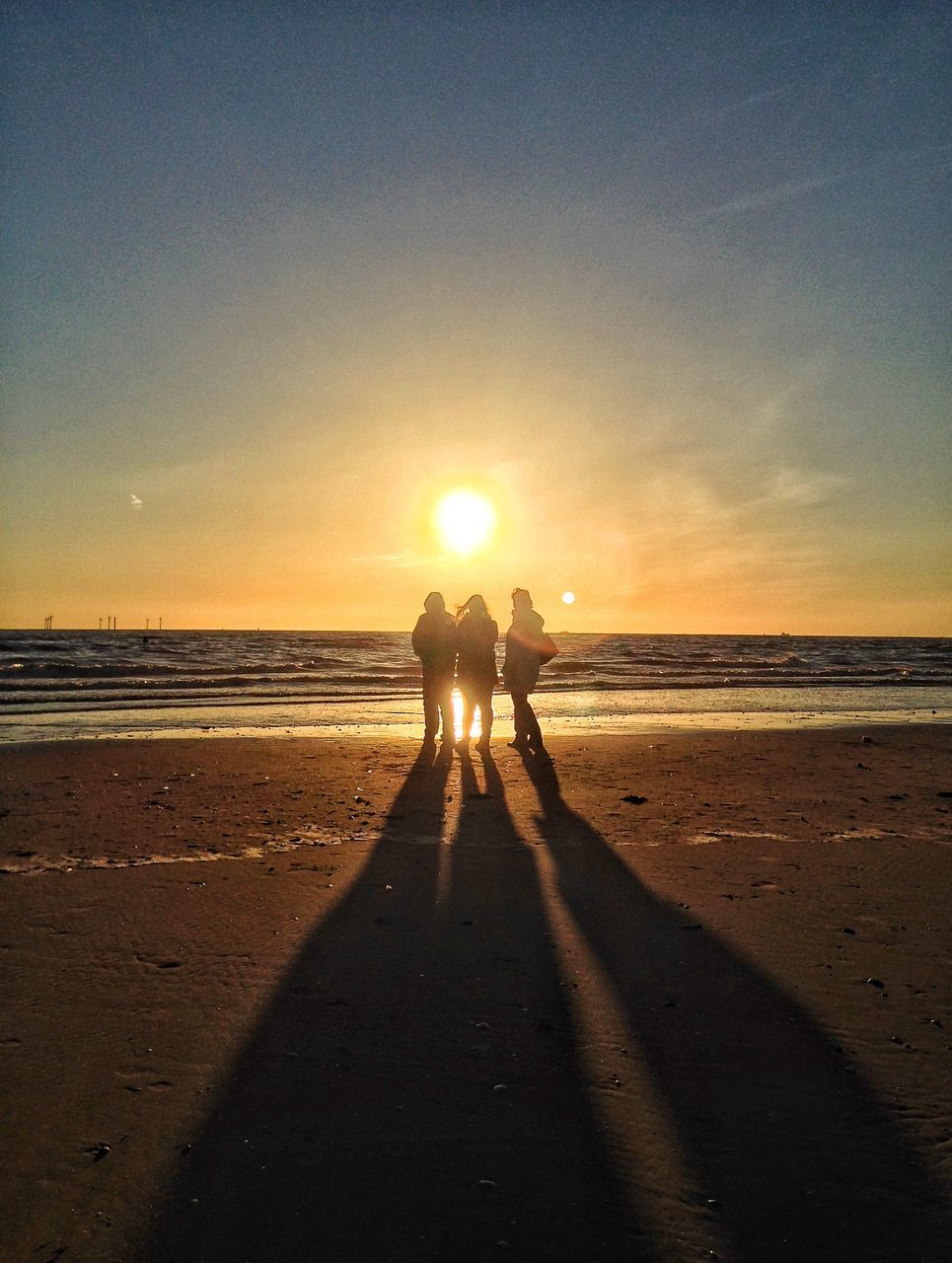 beach, sunset, sea, silhouette, horizon over water, shore, sand, lifestyles, full length, leisure activity, walking, sun, water, togetherness, standing, sunlight, tranquility, tranquil scene