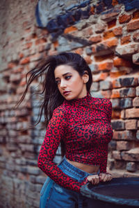 Beautiful young woman standing against wall