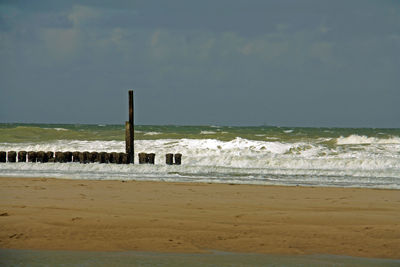 Wooden posts on shore against sky at domburg