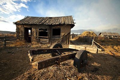 View of house on landscape against cloudy sky