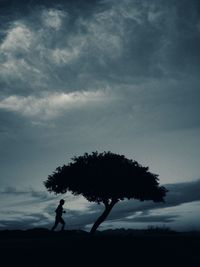 Silhouette of trees against cloudy sky