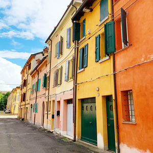 Residential buildings by street against sky
