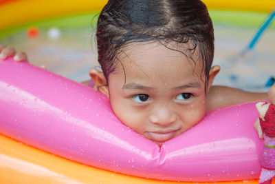 Close-up of girl looking away while leaning on wading pool