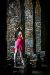 Ballet dancer standing on retaining wall in old building