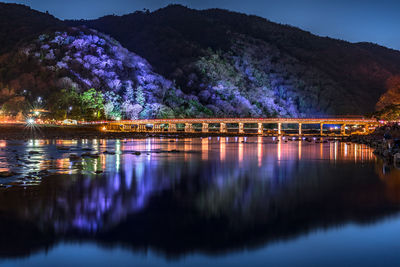 Bridge over river against sky at night