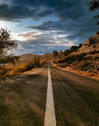 Empty road along landscape against sky