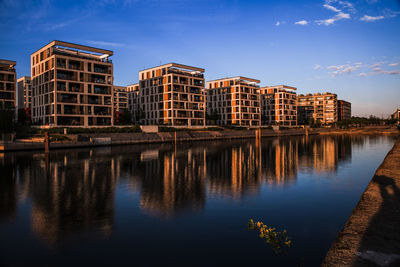 Reflection of buildings in river against blue sky