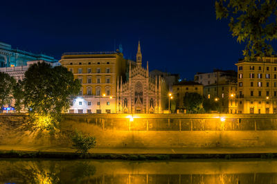 Reflection of buildings in lake at night